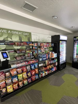 Aisle of a workplace micro-market with stocked shelving and refrigerated cases