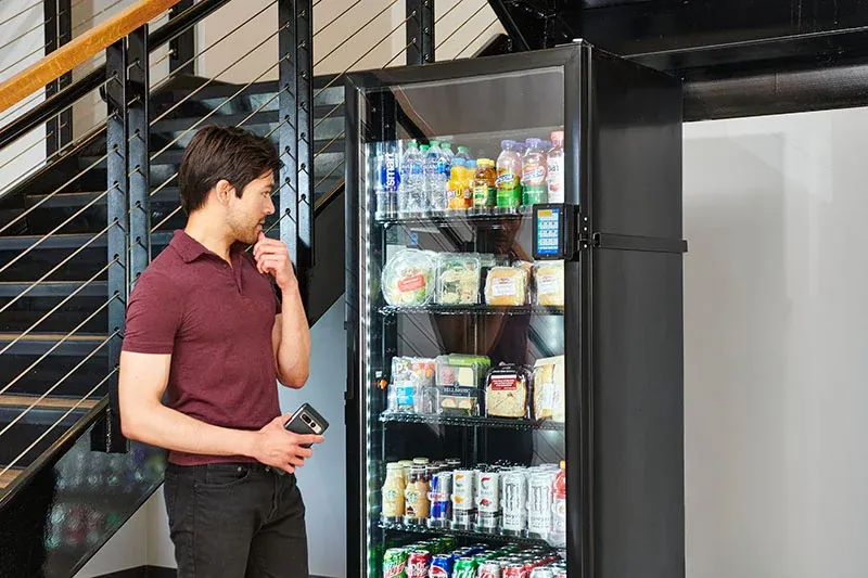 Employee browsing an open smart cooler stocked with drinks and snacks